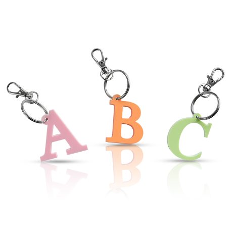 Tres llaveros con iniciales "A", "B" y "C" en colores rosa, naranja y verde, respectivamente, sobre fondo blanco