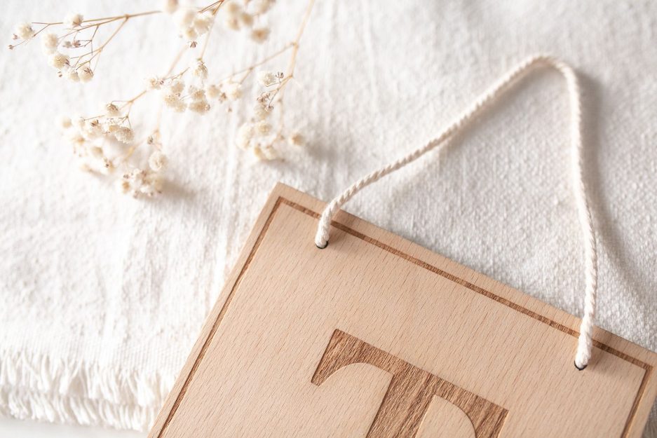 Detalle de cordón de macramé de algodón en banderín de madera de haya con grabado