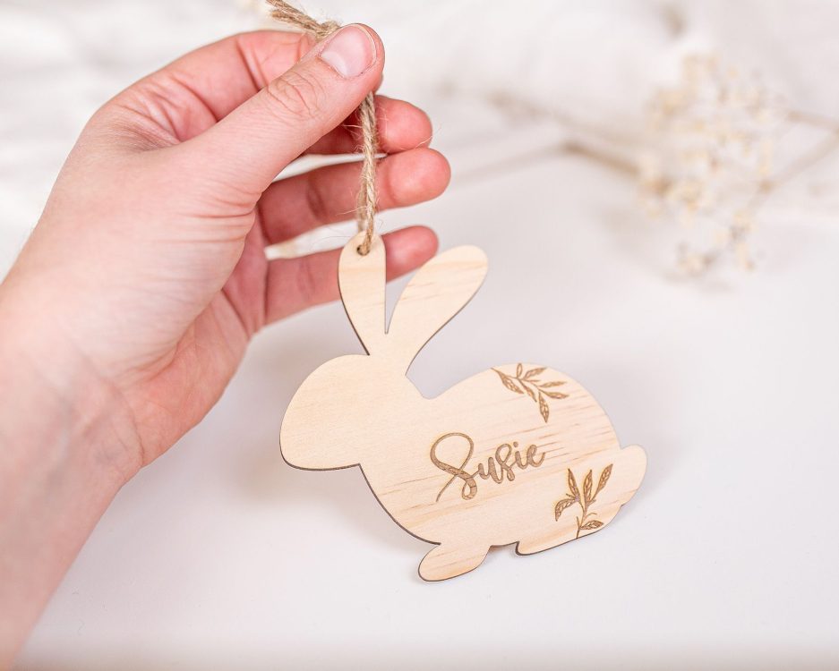 Etiqueta de madera personalizada en forma de conejo con cordón para niños sujeta por una mano